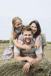 Happy family on hay in field under sky - EYAF02826