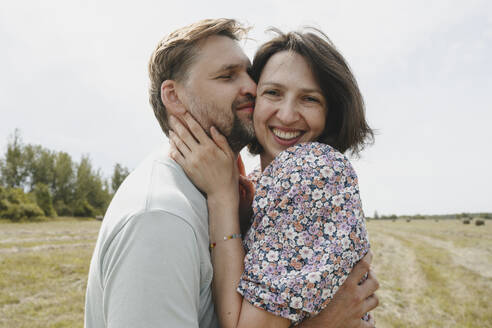 Smiling man hugging and embracing woman in field - EYAF02836