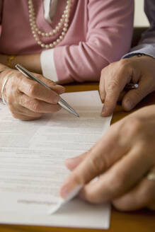 Close up of man and woman hands signing documents - FSIF06389