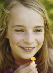 Close up of young blonde girl holding yellow flower - FSIF06392