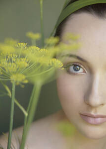 Junge schöne Frau in Gedanken versunken mit gelber Blume - FSIF06398