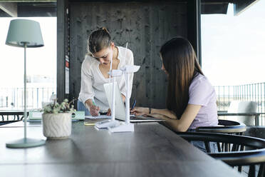 Two young female engineers working at desk on sustainable energy project - ASGF04535