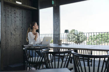 Young woman using laptop at cafe table - ASGF04557