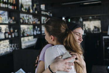 Zwei junge Frauen umarmen sich in einer Bar - ASGF04562