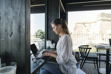 Hübsche Blondine mit Laptop auf dem Tresen eines Cafés - ASGF04603