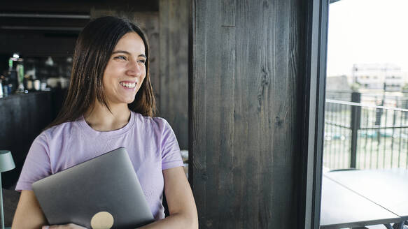 Portrait of beautiful brunette woman holding laptop - ASGF04609