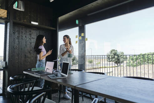 Two young women working together on sustanable resources project at coworking space - ASGF04614