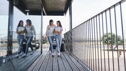 Two young women walking side by side on balcony - ASGF04631