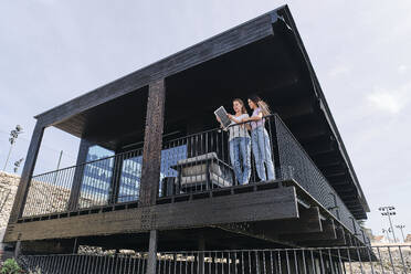 Two young women talking on balcony - ASGF04636