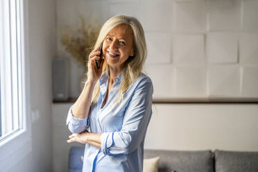 Happy woman talking on mobile phone at home - DLTSF03642