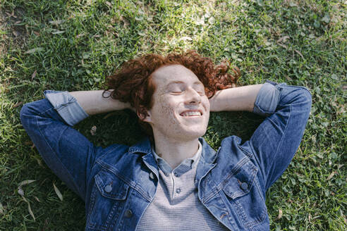 Smiling young man relaxing on grass - DSIF00703