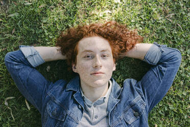 Young man with hands behind head lying on grass - DSIF00705