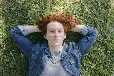 Young redhead man with hands behind head lying on grass - DSIF00706