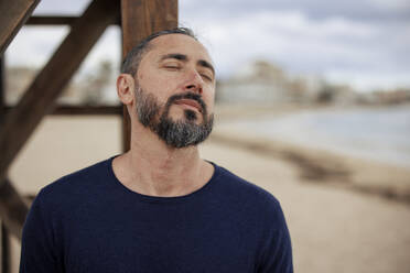 Mature man with eyes closed at beach - JOSEF21035