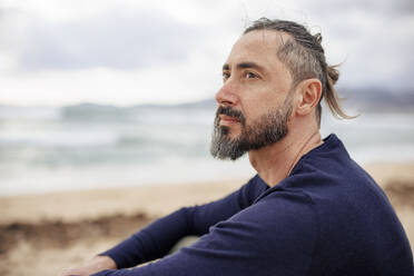 Nachdenklicher Mann mit blauem T-Shirt am Strand - JOSEF21040