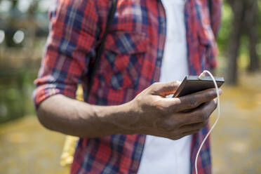 Hand eines jungen Mannes, der ein Smartphone benutzt - IKF01234