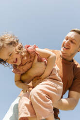 Niedriger Winkel von fröhlichen jungen Vater hält glücklich kleine Tochter Spaß zusammen auf sonnigen Tag gegen blauen wolkenlosen Himmel - ADSF46971
