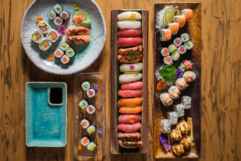 Top view of various sushi with assorted fish near rolls with different topping served on wooden table in light cafe - ADSF47002