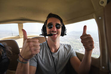 Stock photo of happy man wearing aviation headset enjoying light aircraft tour and looking at camera. - ADSF47036