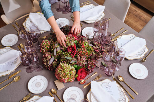 Von oben der Ernte anonyme weibliche Florist arrangieren sortiert blühenden Blumen auf Bankett-Tabelle mit serviert Geschirr und Besteck - ADSF47064