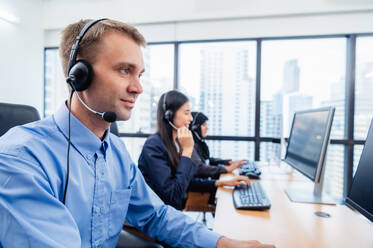 Group of young profession call center operator agent with headsets working in office. Business telemarketing service people concentrating on having conversation work and talking to customer friendly - INGF12083