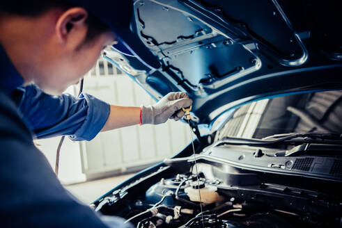Car mechanic holding checking gear oil to maintenance vehicle by customer claim order in auto repair shop garage. Engine repair service. People occupation and business job. Automobile technician - INGF12088