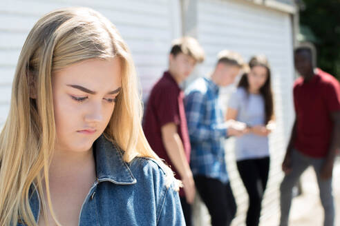 Unhappy Teenage Girl Being Gossiped About By Peers - INGF12099