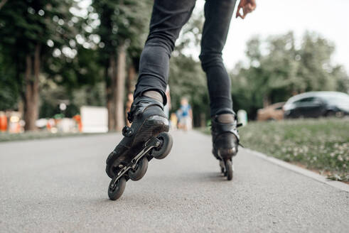 Roller skating, young skater rolling in summer park, back view on legs. Urban roller-skating, active extreme sport outdoors, youth leisure, rollerskating lifestyle - INGF12107