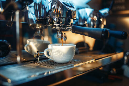 Espresso machine pours fresh black coffee into the cup closeup, nobody. Professional restaurant, cafe or cafeteria business equipment. Espresso machine pours fresh black coffee closeup - INGF12116