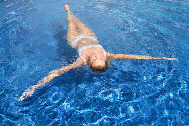 Hohe Winkel der barfuß weiblichen Touristen in weißen Bikini Schwimmen in sauberen Pool Wasser mit Augen geschlossen, während der Ausgaben Sommerurlaub im Resort - ADSF47084