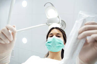 Zahnarzt mit chirurgischer Maske bei der Arbeit in einer Zahnklinik - PGF01626