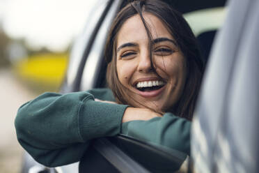 Happy woman leaning on car window - JSRF02619