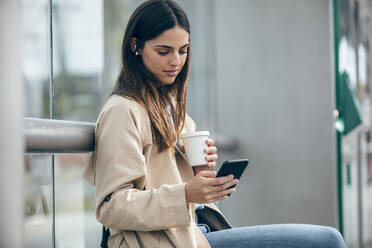 Junge Frau mit Kaffeetasse und Smartphone - JSRF02623