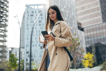 Junge Frau benutzt ein Mobiltelefon in der Stadt - JSRF02630