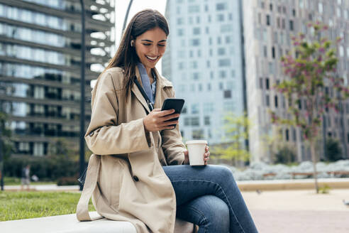 Glückliche Frau mit Mobiltelefon vor einem Gebäude - JSRF02633