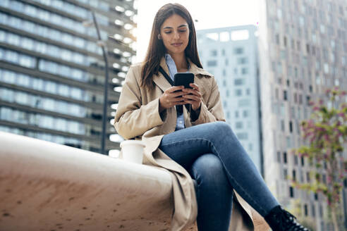 Lächelnde Frau mit Mobiltelefon vor einem Gebäude - JSRF02634