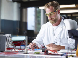 Scientist working over circuit board in laboratory - CVF02486