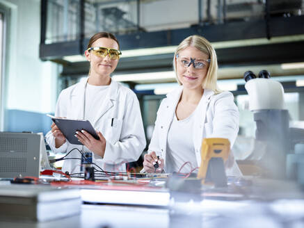 Smiling young scientists working in electronics laboratory - CVF02493