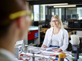 Lächelnde Wissenschaftler bei der Arbeit an einer Werkbank im Labor - CVF02495