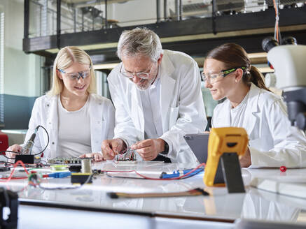 Professor teaching trainees with circuit board in laboratory - CVF02503