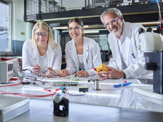 Happy engineers with circuit boards and equipment in laboratory - CVF02511