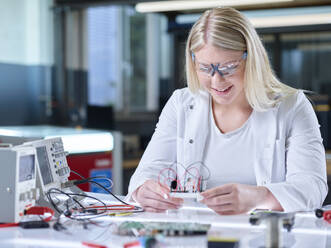 Happy trainee working over circuit board in laboratory - CVF02512