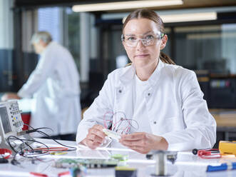 Smiling trainee working over circuit board in laboratory - CVF02513