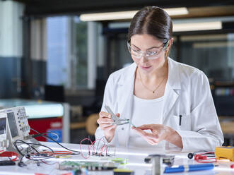 Trainee measuring circuit board with caliper in laboratory - CVF02514