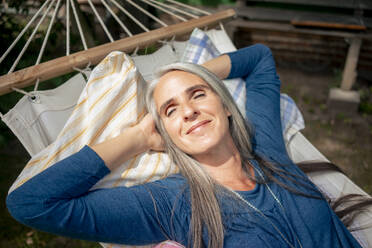 Lächelnde Frau entspannt sich in der Hängematte an einem sonnigen Tag - KNSF09831