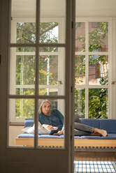 Ältere Frau mit Tablet-PC auf dem Sofa zu Hause - KNSF09841