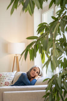 Reife Frau entspannt sich auf dem Sofa zu Hause - KNSF09853