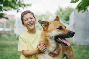 Happy boy with dog in back yard - NLAF00139