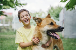 Glücklicher Junge mit Hund im Hinterhof - NLAF00139
