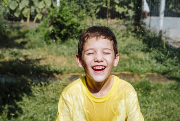 Happy boy playing with water in back yard on sunny day - NLAF00146